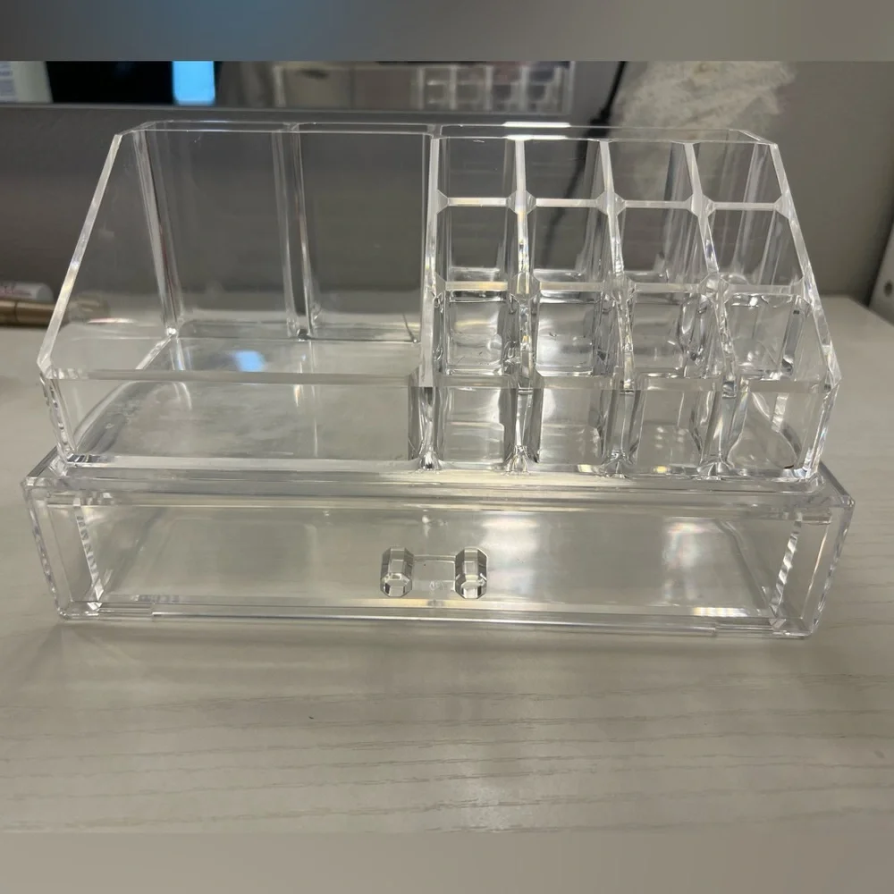 A clear makeup storage container with a drawer